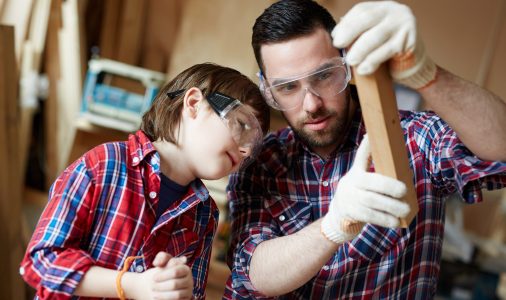 Man and his son looking at wooden workpiece before processing it